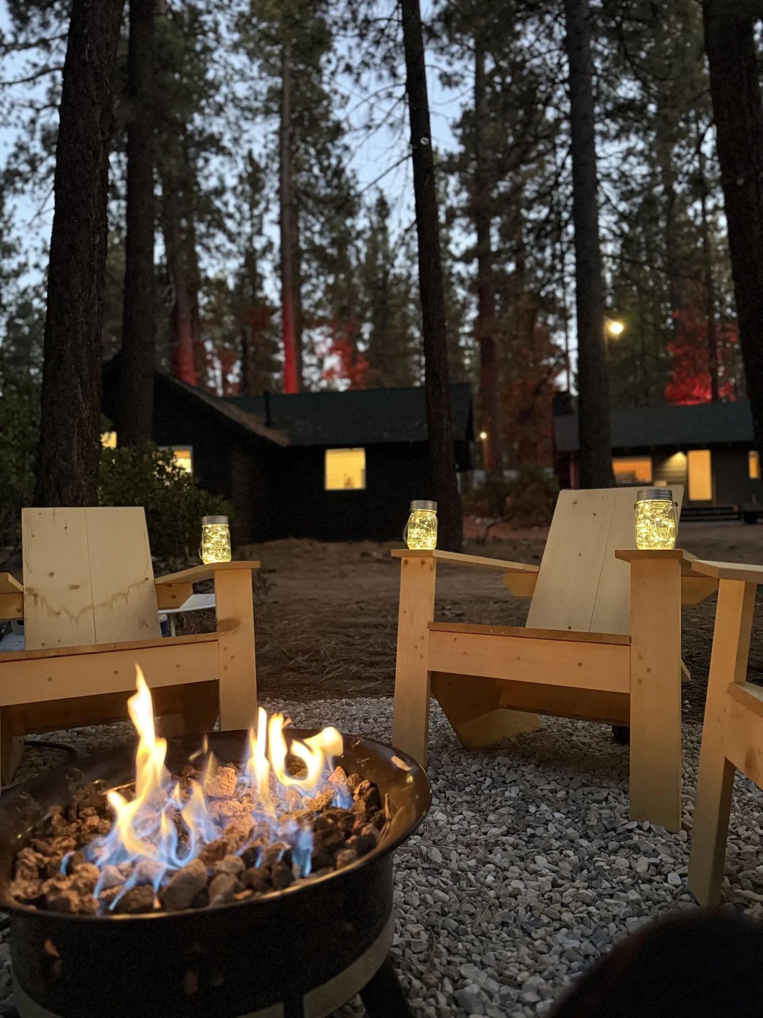Adirondack chairs outside Colorado Lodge cabins at dusk with warm lights glowing from the cabin windows in Big Bear Lake