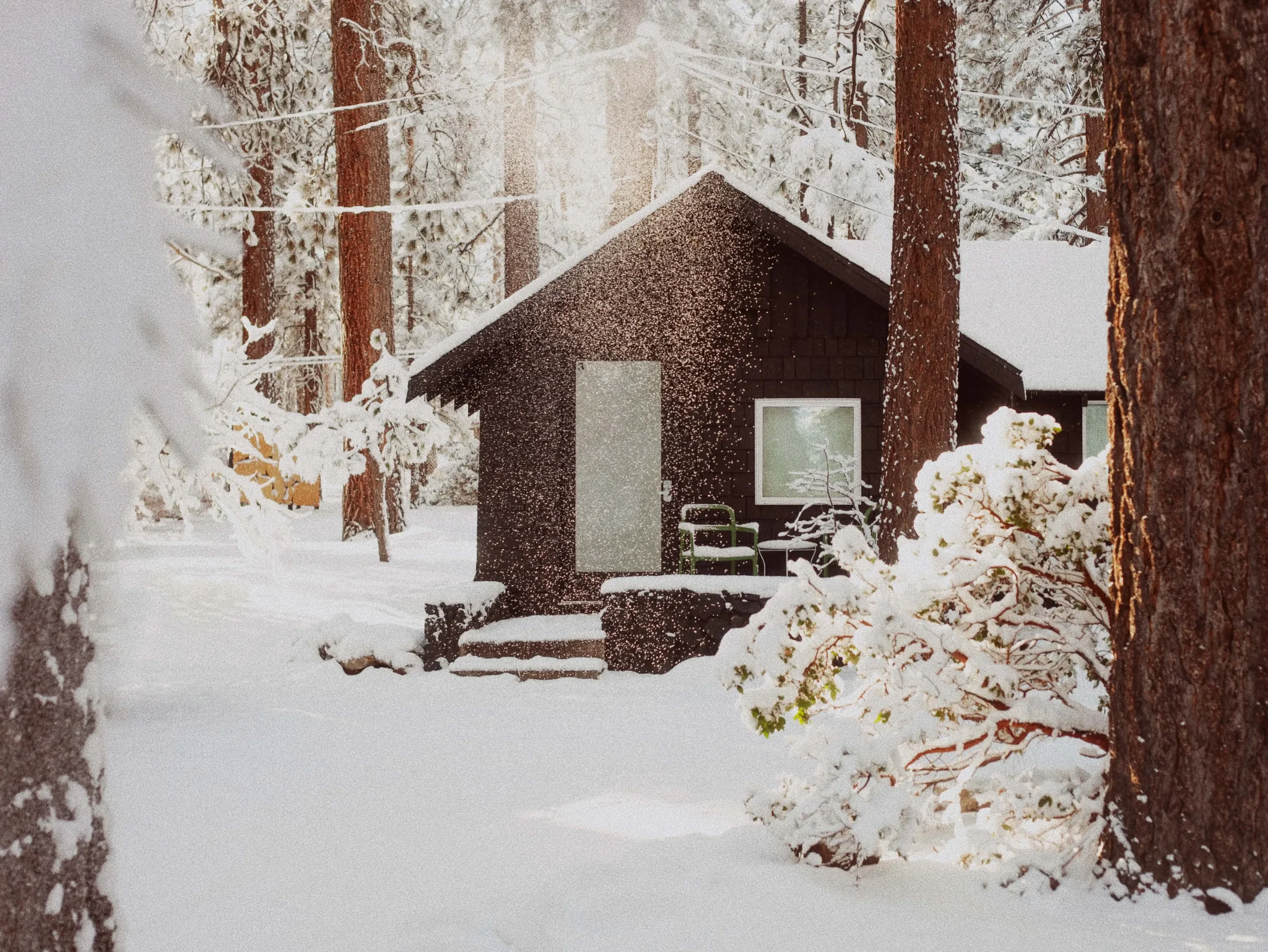 Modern cabin exterior in winter snow with sunbeam at Colorado Lodge boutique lodge in Big Bear Lake California