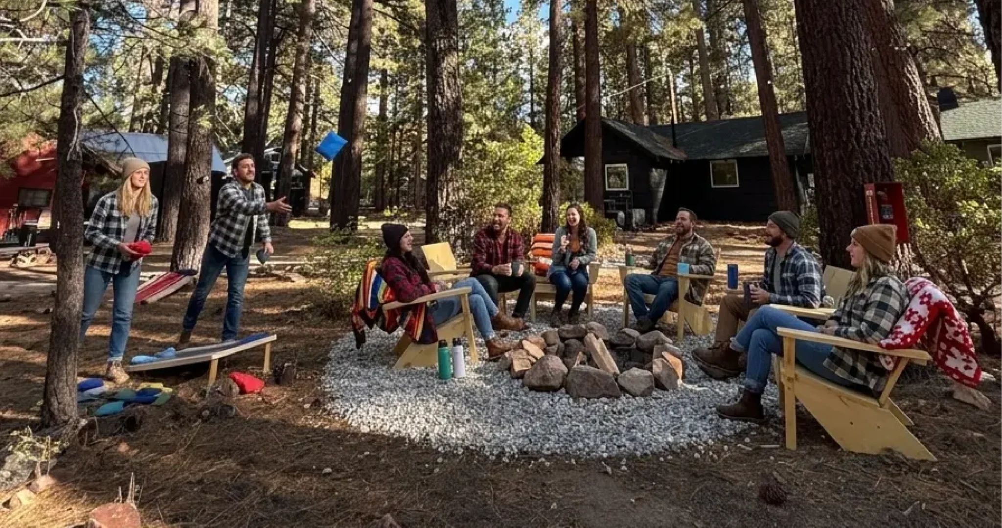 Group gathered around the community fire pit with cornhole on the lawn at Colorado Lodge in Big Bear Lake, available as a full-property group buyout