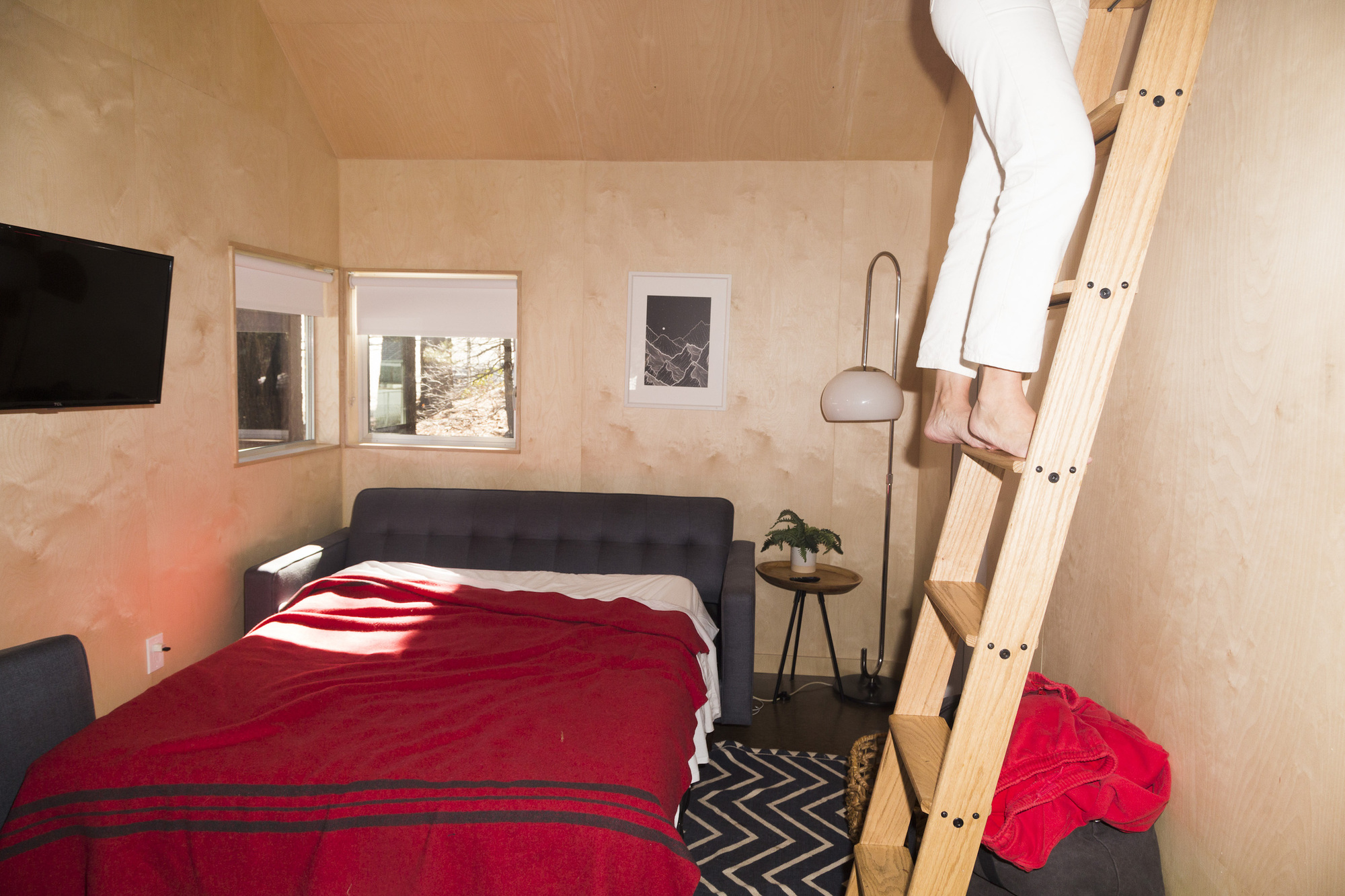Guest climbing the wood loft ladder inside a birch paneled cabin at Colorado Lodge in Big Bear Lake