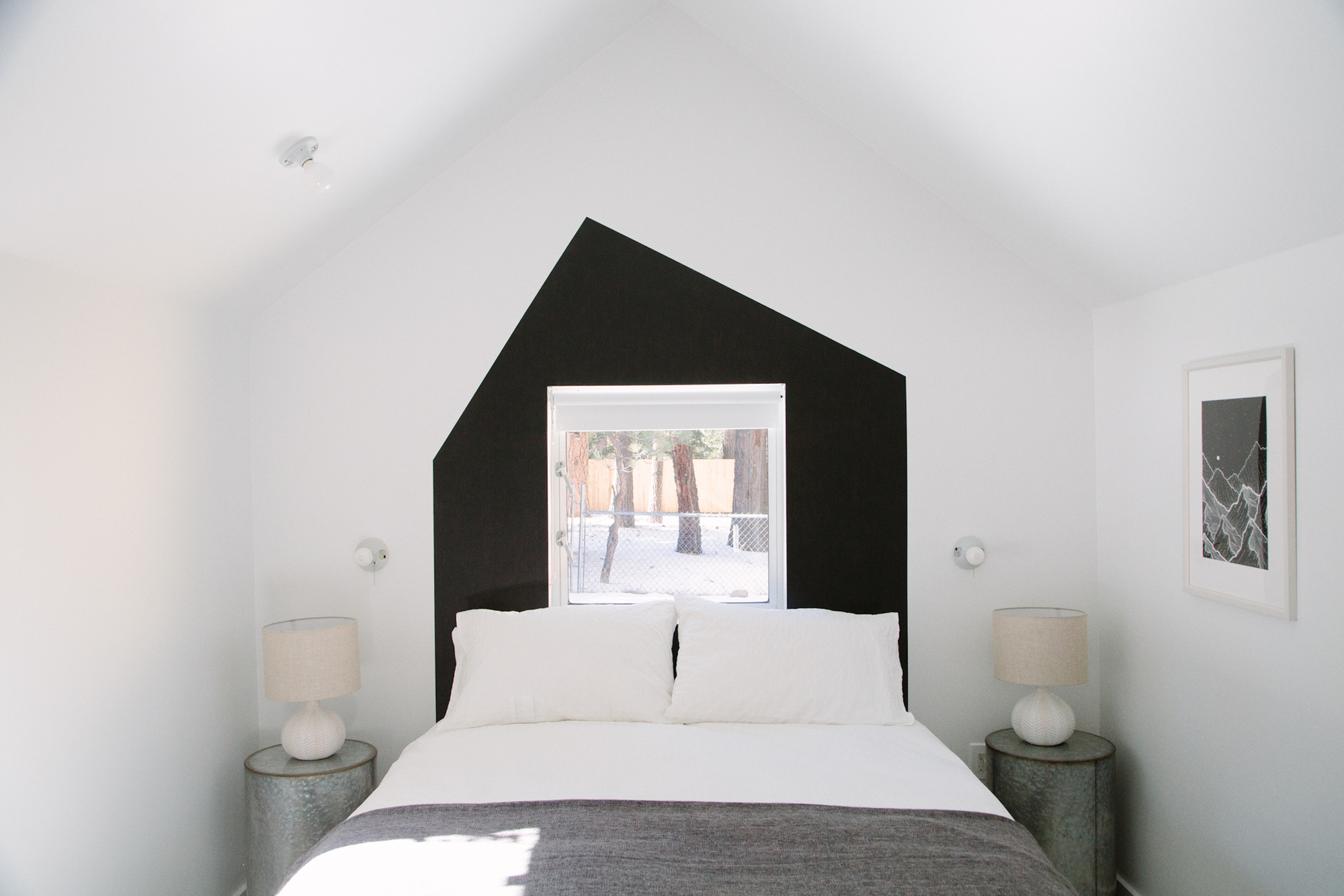 Minimalist white cabin bedroom with black gable accent wall at Colorado Lodge in Big Bear Lake
