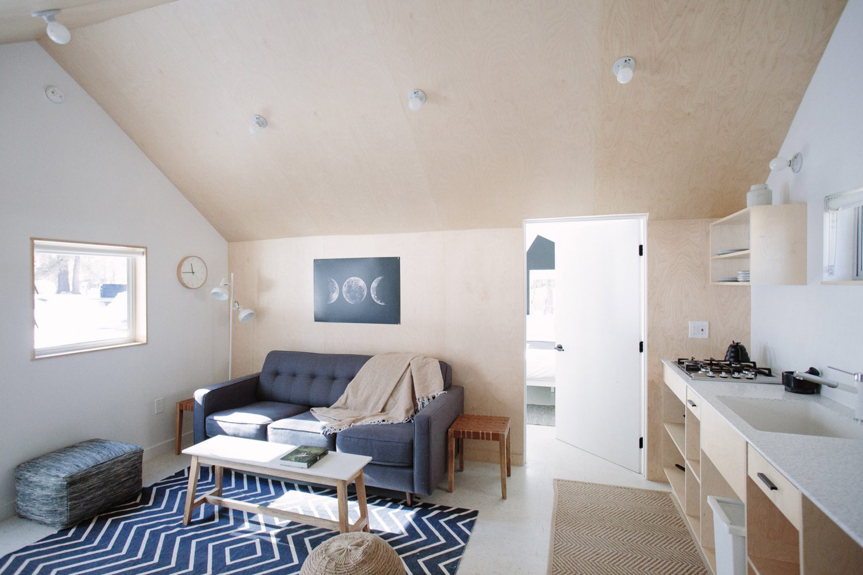 Bright cabin living room with blue sofa, chevron rug, and birch kitchenette at Colorado Lodge in Big Bear Lake