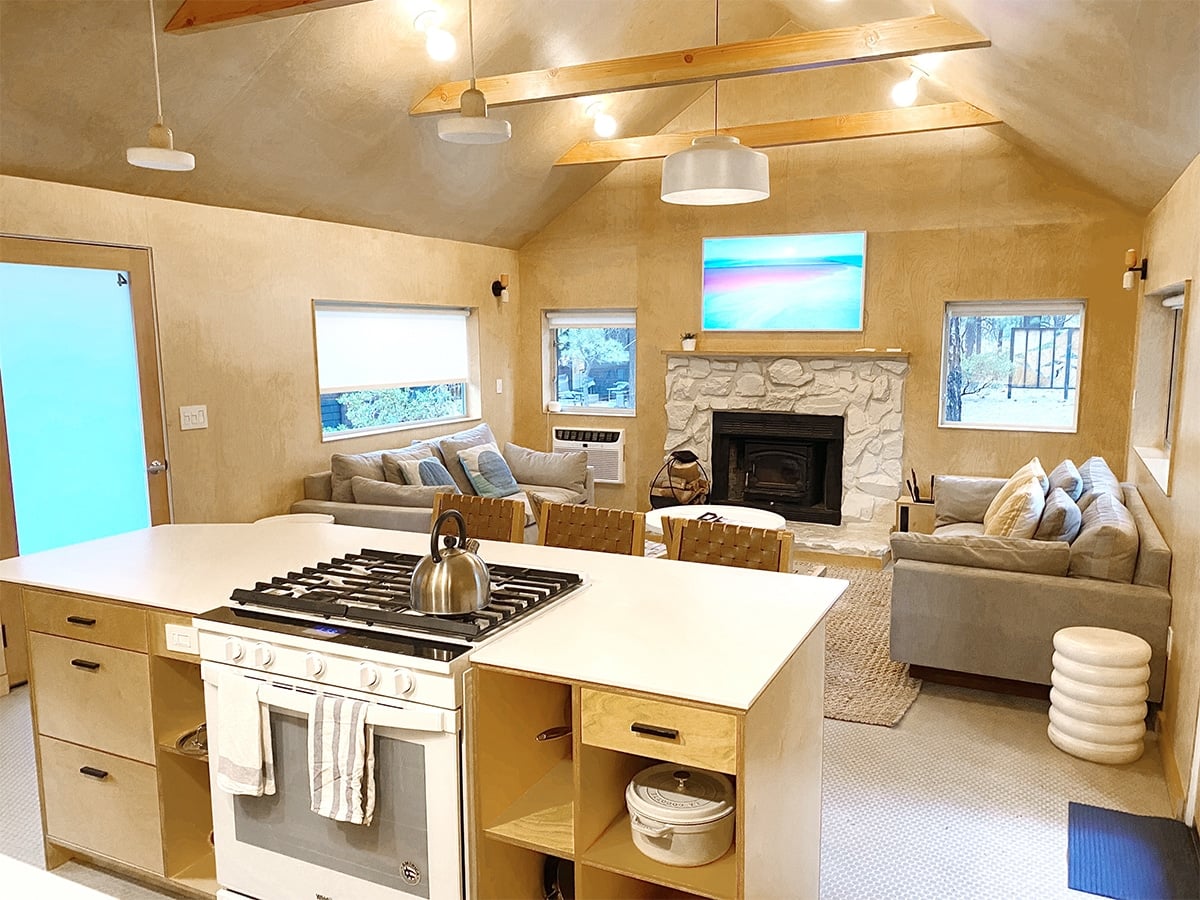 Open plan cabin kitchen and living room with vaulted wood ceiling and stone fireplace at Colorado Lodge, Big Bear Lake